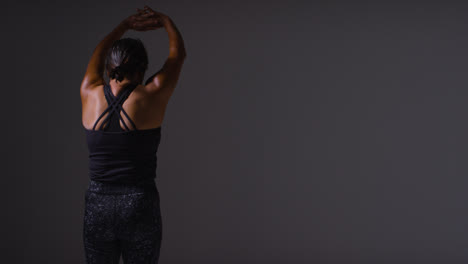 Studio-Shot-Showing-Back-Of-Mature-Woman-Wearing-Gym-Fitness-Clothing-Doing-Stretching-Exercises-1